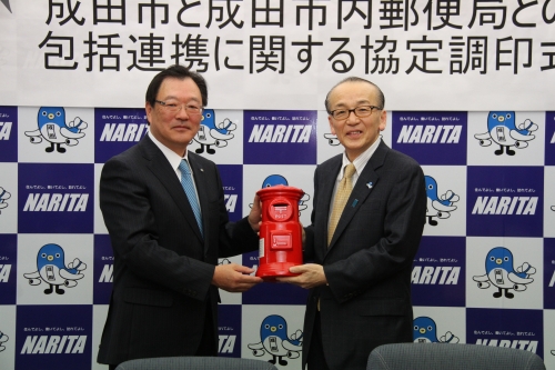 成田郵便局と成田市の調印式で包括連携協定の締結を記念して、記念品の贈呈を行う様子