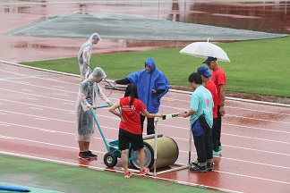 雨天のなか、ボランティアスタッフが競技場を整備する様子