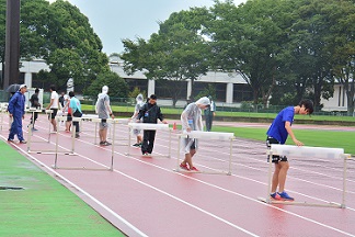 雨天のなか、ボランティアスタッフがハードルを設置する様子