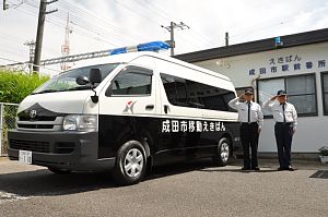 移動えきばんの大型バンタイプの車の脇で2名の駅前番所員が敬礼をしている様子