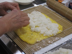 卵焼きの上にすしめしを広げている様子