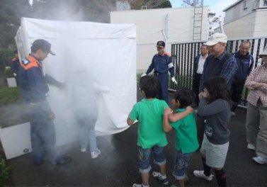 自主防災訓練の様子13。赤坂消防署員の指導のもと、煙の怖さを体験する住民と子供達。