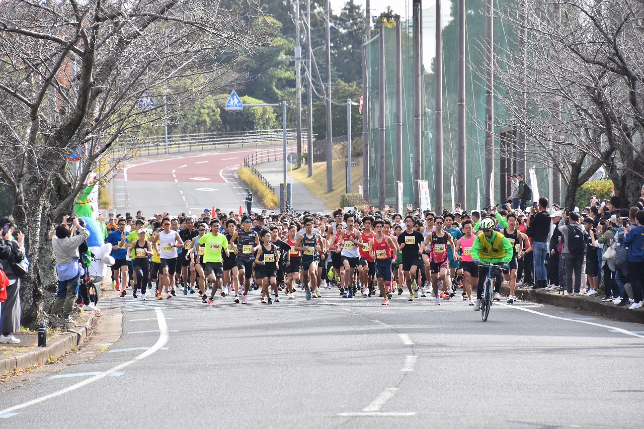 沿道に多くの応援者が並ぶ中で、ランナーがスタートする様子。先導する自転車に導かれながら勢いよくランナーが走り出し、後方までその列が続いている。