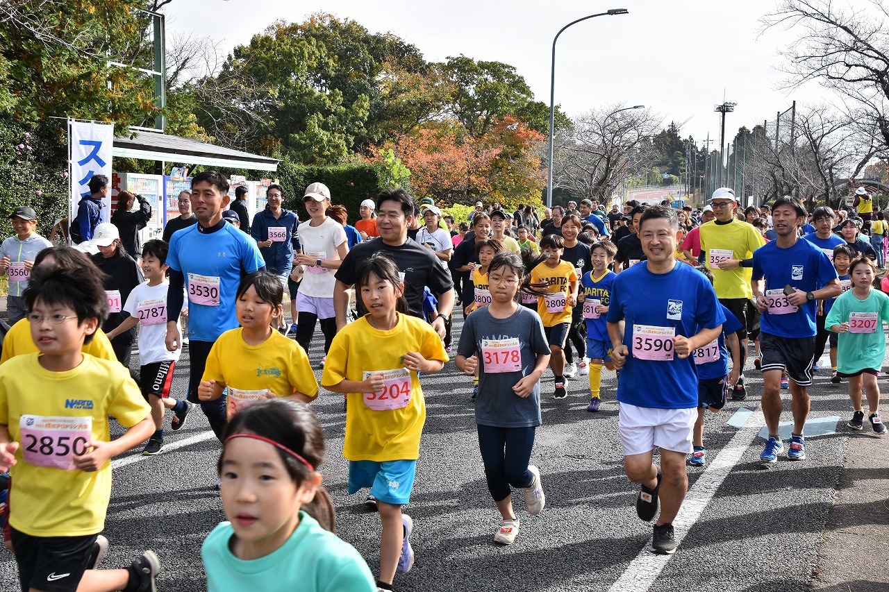 オープンの部に参加した子どもから大人までのランナーが笑顔でコースを走る様子。ランナーの中には参加賞として配布したTシャツを着用している人も多い。