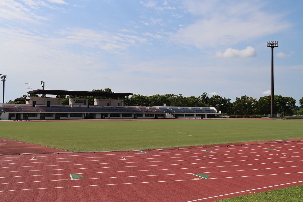中台運動公園陸上競技場の雰囲気が分かるように、場内から撮影したイメージ写真。青空の下、陸上競技のトラックの内側に芝生のグラウンドが広がり、奥にはスタンドが見える。