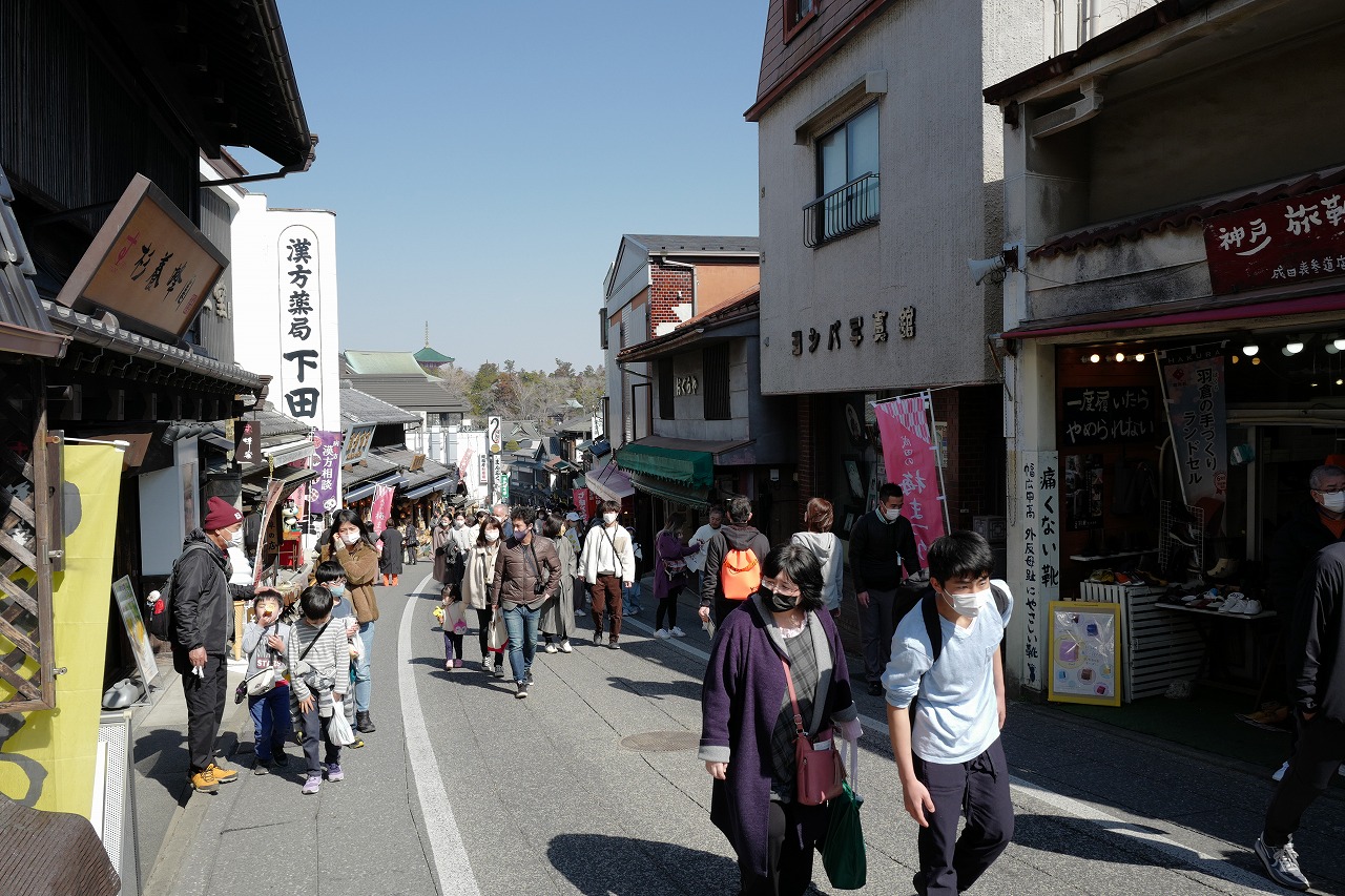 成田山表参道の写真。道の両側には風情のある店舗が立ち並び、道の先には成田山新勝寺の三重塔の先端が見える様子。