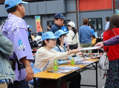表参道沿いの会場で案内を渡す学生
