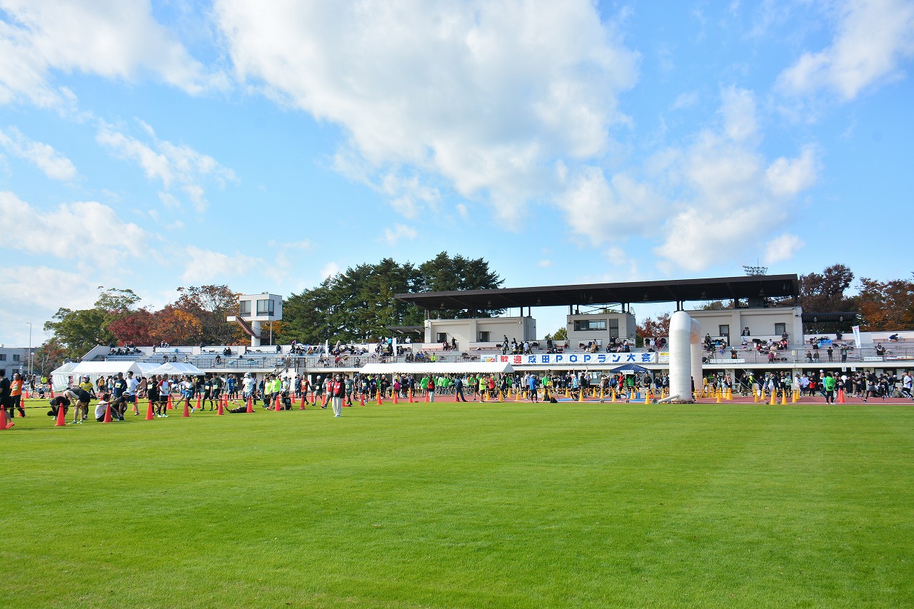 2025成田POPラン大会の会場全体の様子の写真。秋晴れの下、ランナーが続々とゴールする様子が写っている。