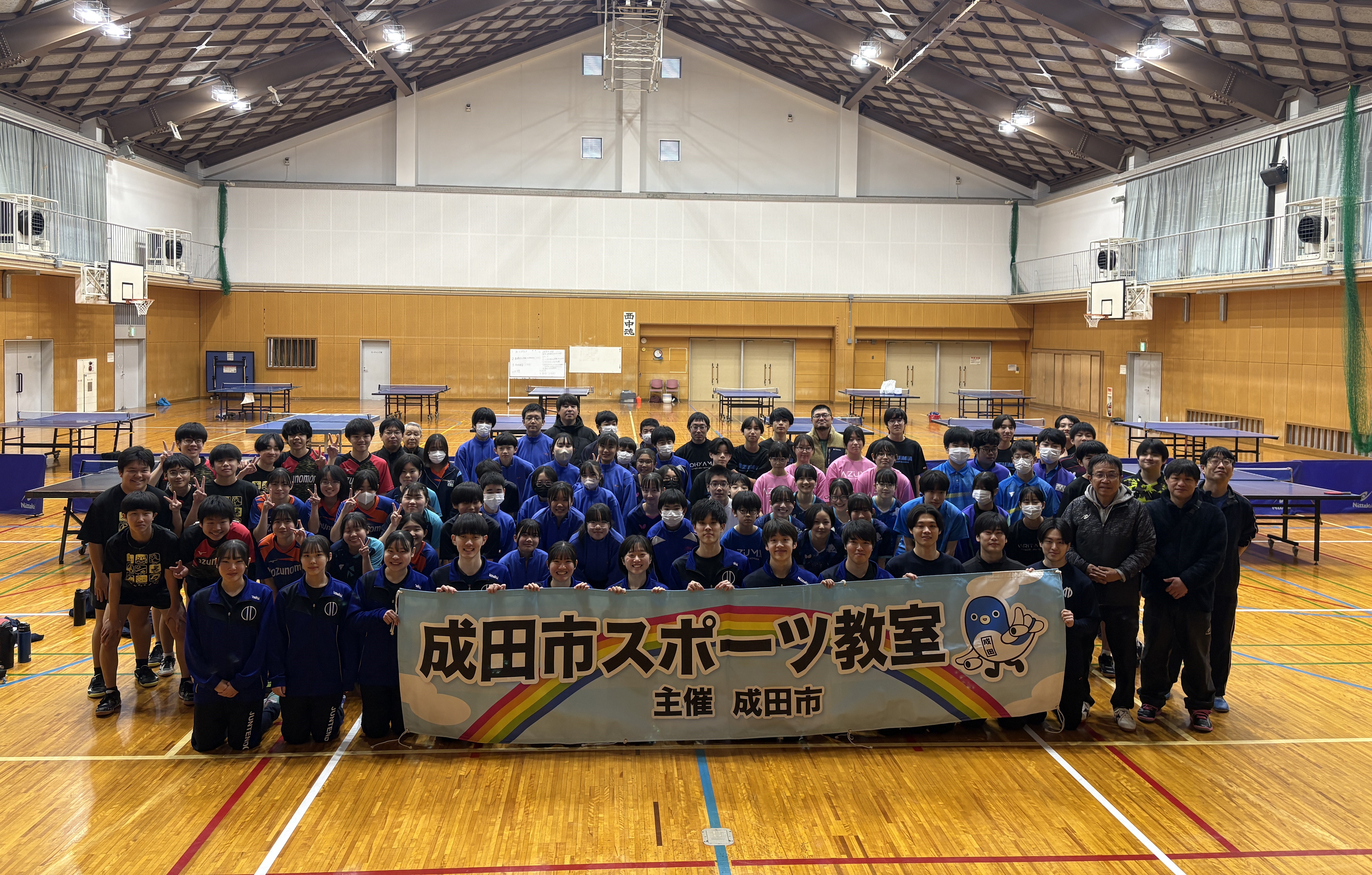 集合写真。卓球教室で講師を務めた順天堂大学の皆さん、参加した中学生の皆さんが笑顔で写っている。