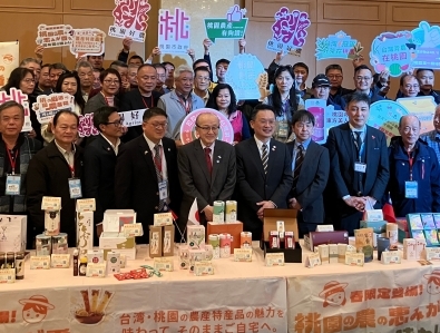 物産品を前に関係者と記念撮影を行う様子